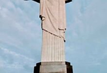 Imagem impressionante do Cristo Redentor, majestosamente situado no topo do morro do Corcovado, no Rio de Janeiro. A estátua icônica com os braços abertos em um gesto de acolhimento e paz, contrastando com o céu azul e a paisagem exuberante ao redor. Uma representação imponente da cultura e da fé brasileira.